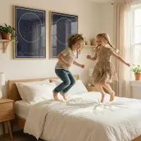 Kids jumping from a bed with starrymaps prints behind them