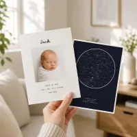 A hand holding a baby announcement card beside a navy star map card printed for the same night