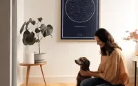 Woman with a dog and a starrymaps.com print on the wall, wide shot.
