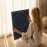 Woman sitting by a window looking at a personalised navy star map poster